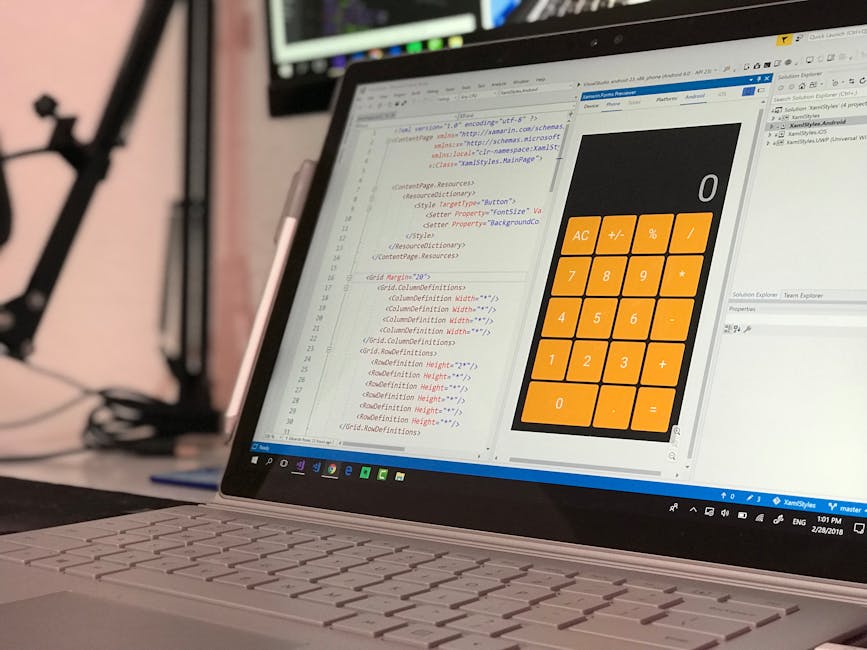A close-up of a laptop computer displaying a spreadsheet with code on the left side and a large digital calculator interface with orange buttons on the right, set on a desk in an office environment. T